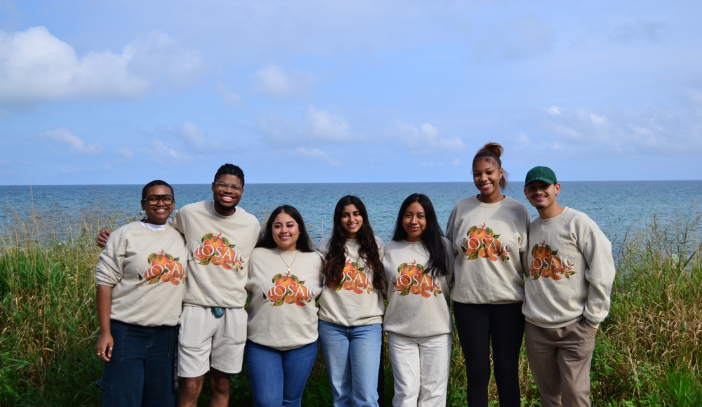MOSAIC student leaders posing in front of Lake Michigan, wearing MOSAIC branded crewnecks